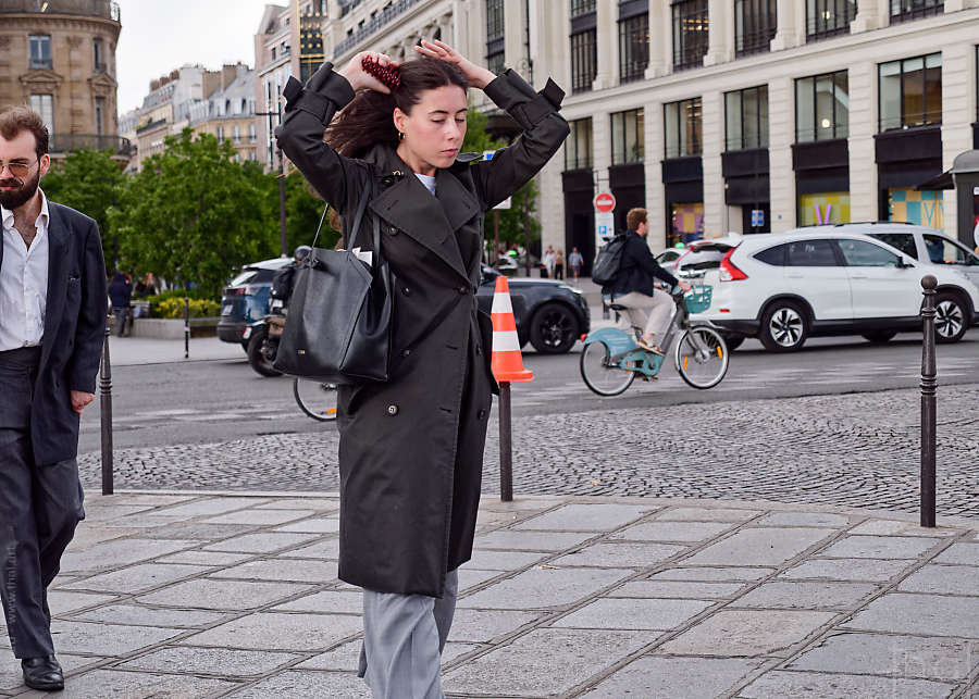 A woman fixing her hair while standing on a traffic cone on the Pont Neuf