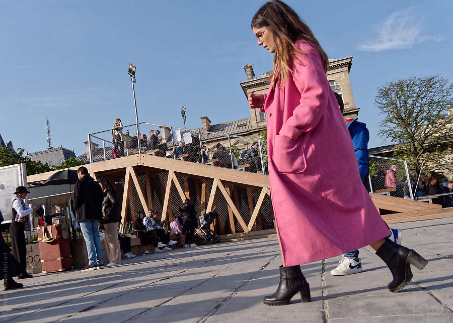femme en manteau rose avec des chaussures à talon quittant le parvis de Notre-Dame