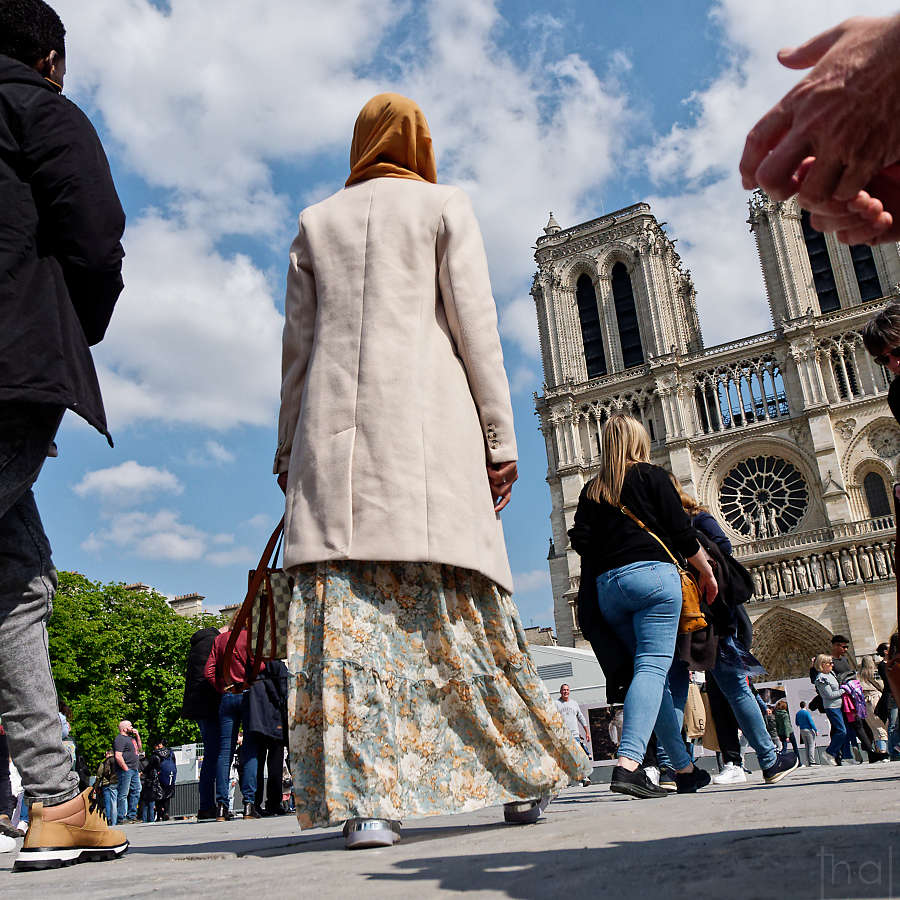femme de dos recouverte d'un foulard devant Notre-Dame à Paris