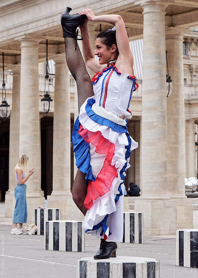 Danseuse de French Cancan faisant un grand écart vertical devant une colonnade