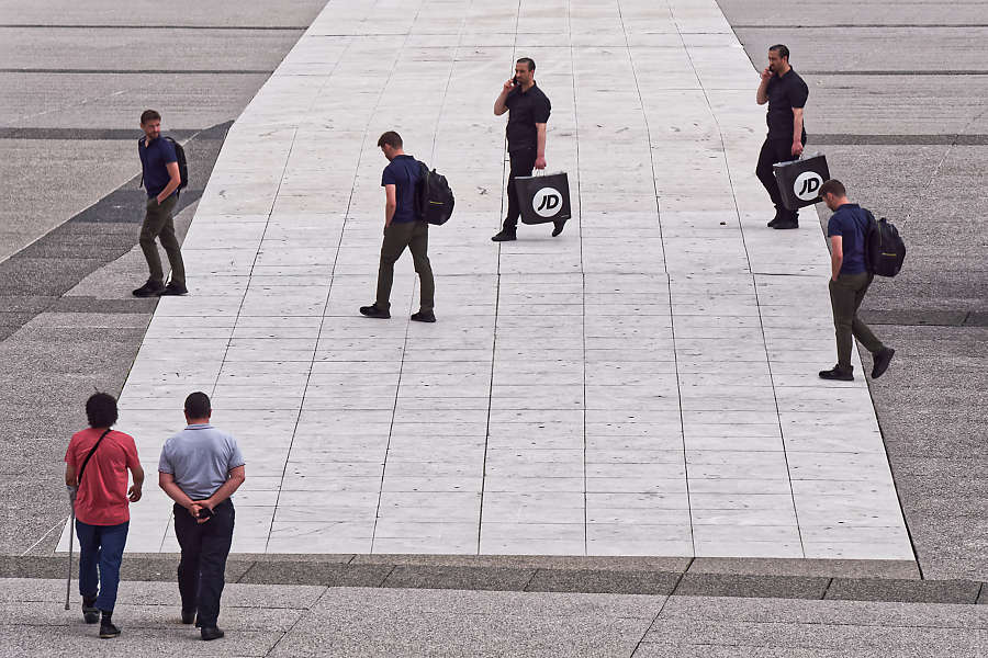 Photomontage de passants dédoublés traversant une zone pavée
