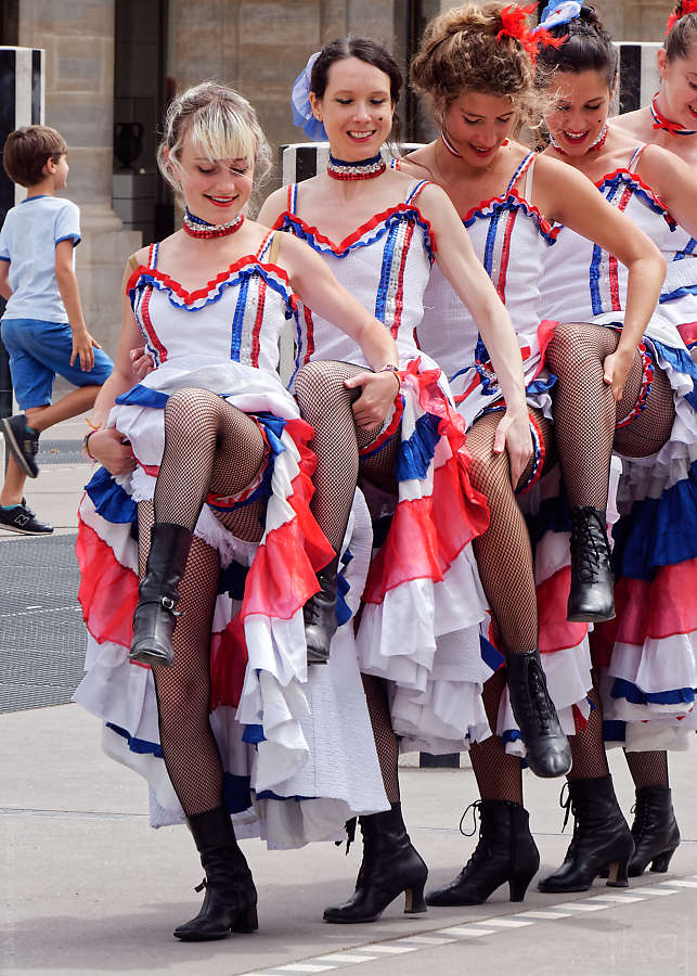 Enfant levant la jambe en même temps qu'un groupe de danseuse de French Cancan