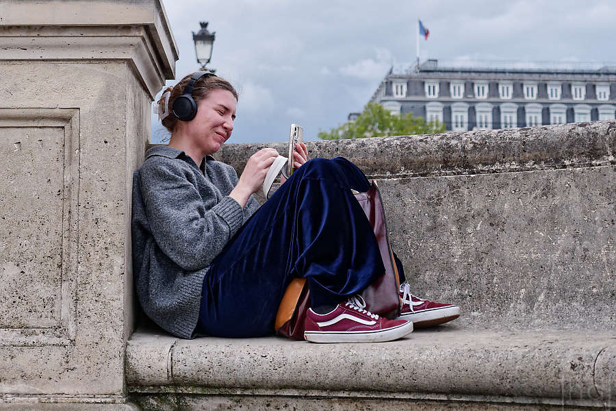 A woman smiling at her cell phone in a niche on the Pont Neuf