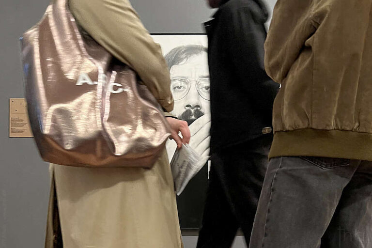 Visitors passing by a photograph of Jean-Claude Guillaumon yawning