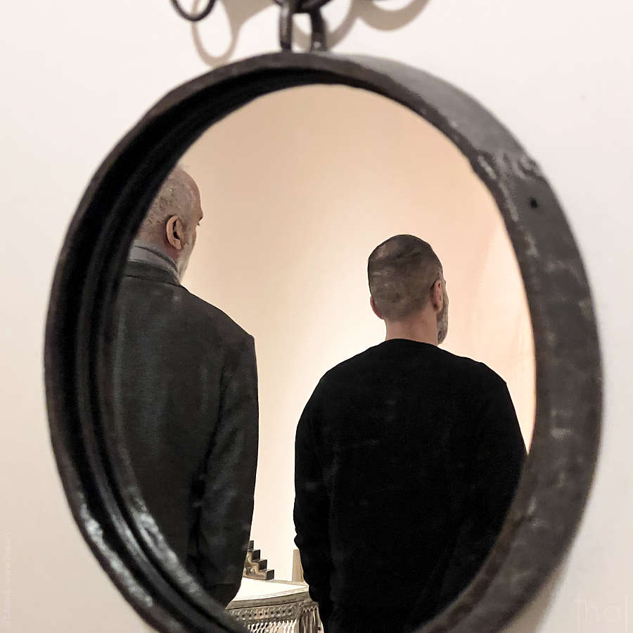 deux hommes se reflétant de dos dans un miroir rond au Salon du PAD