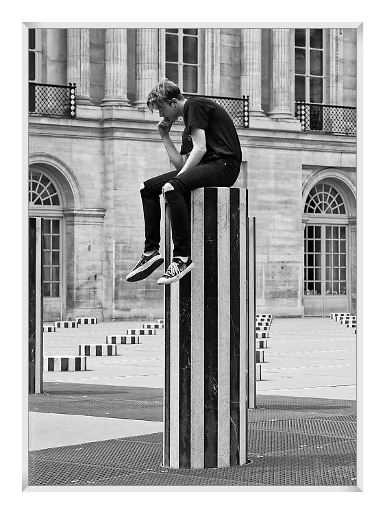 Homme imitant le penseur de Rodin sur une colonne de Buren dans la cour du Palais Royal